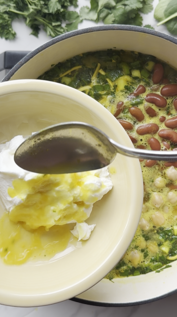 broth being mixed in with yogurt to prevent curdling